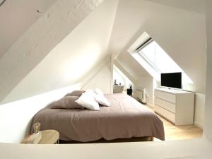 a white bedroom with a bed and a window at LA CLE DES TOITS in Colmar