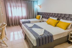 two beds in a hotel room with yellow and blue pillows at Baía Branca Beach Resort in Tamandaré