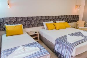 two beds in a hotel room with yellow pillows at Baía Branca Beach Resort in Tamandaré
