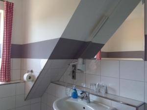 ein Badezimmer mit einem Waschbecken und einer gestreiften Wand in der Unterkunft Schmidt's Pension Schwansee in Groß Schwansee