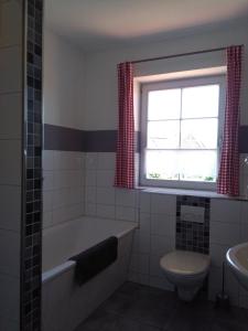 ein Bad mit einer Badewanne, einem WC und einem Fenster in der Unterkunft Schmidt's Pension Schwansee in Groß Schwansee