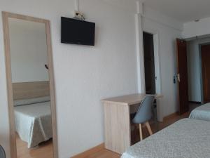 Habitación con escritorio y TV en la pared. en Hotel Condestable, en Benidorm