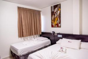 a hotel room with two beds and a window at Bougainville Barreiras in Barreiras