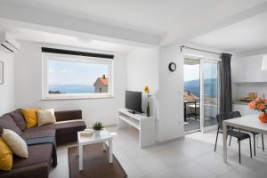 a living room with a couch and a tv and a table at Lemechi Casa Girasole Apartments in Rabac