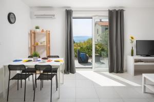 ein weißes Esszimmer mit einem Tisch und Stühlen sowie einem Fenster in der Unterkunft Lemechi Casa Girasole Apartments in Rabac