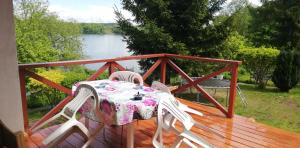 a table and chairs on a deck with a view of a river at Domek na Mazurach in Mrągowo