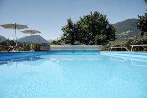 梅拉諾的住宿－Pension Appartment Hecherhof，一个带椅子和遮阳伞的大型蓝色游泳池