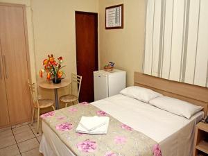 a small room with a bed and a table with a table at OYO Center Hotel, Ribeirão Preto in Ribeirão Preto
