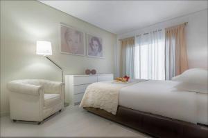 a white bedroom with a bed and a chair at InLoveApartments - City Center With Charm in Lisbon