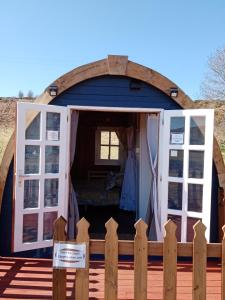 a tiny house with a door and a fence at Wee Hoose Glaping Pod 2 in Skail