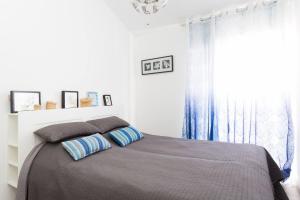 1 dormitorio con 1 cama con cortinas azules y ventana en BuenaVista in Los Cristianos, en Arona