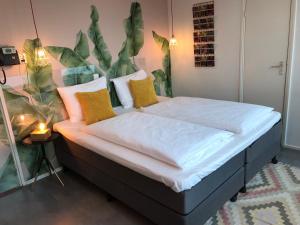 a bedroom with a bed with white sheets and yellow pillows at Hotel Credible in Nijmegen