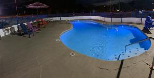 una piscina por la noche con sillas y sombrilla en Log Cabin Inn, en Bay Minette