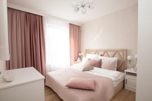 um quarto com uma cama branca e almofadas cor-de-rosa em Komfortowy Apartament PASTELOWY - 2 sypialnie em Kolobrzeg