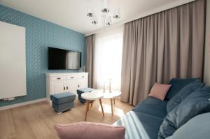 a living room with a blue couch and a tv at Komfortowy Apartament PASTELOWY - 2 sypialnie in Kołobrzeg