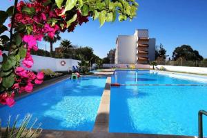 a large swimming pool with blue water and pink flowers at Vista Mar em todo apartamento in Portimão