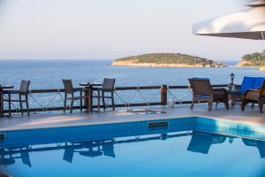 a swimming pool with chairs and tables next to the ocean at Barbagiannis House in Ormos Panagias