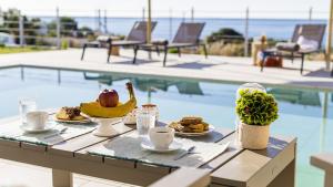 a table with food on it next to a swimming pool at Kiotari Akti Beachfront Villas in Gennadi