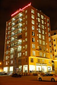 a building with a sign on top of it at night at Alpha Suites Hotel in Salalah