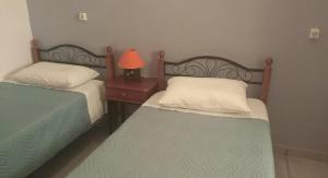 two beds in a bedroom with a lamp on a night stand at Ktima Edem in Kamares