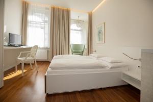 una camera da letto bianca con un letto e una scrivania di Hotel Gollner a Graz
