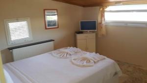 una camera da letto con un letto con lenzuola bianche e una TV di Ciftlik Hotel a Çeşme