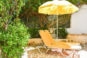 a yellow chair and an umbrella on a patio at Jasmine Home, Aegina City in Aegina Town +22 photos