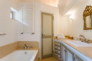 a bathroom with a tub and a sink and a mirror at La Ferme du Haut Trigaud in Bonnieux