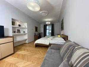 um quarto com uma cama, um sofá e uma televisão em P&J Apartments Floriańska em Cracóvia