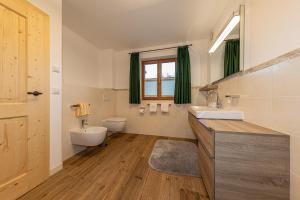 een badkamer met 2 wastafels, een toilet en een raam bij Ferienhaus STOARÖSERL in Mittenwald