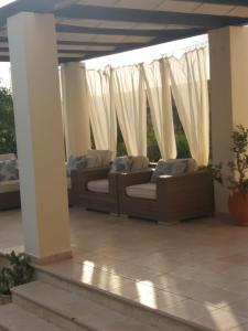 two couches on a patio with white curtains at Villa Koumneni in Pano Akourdalia