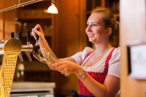 una mujer está vertiendo vino en una copa en Hotel Hachinger Hof, en Oberhaching