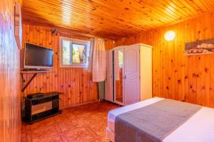 a bedroom with a bed and a flat screen tv at Les Bungalows des Makes in Makes