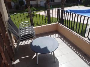 a balcony with two chairs and a table and a pool at SDB Alojamientos in Puerto de Mazarrón