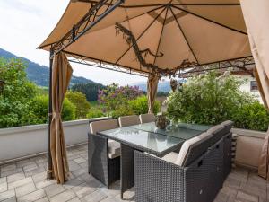 een terras met een tafel, stoelen en een parasol bij Appartement Baumgartner in Westendorf +22 foto's