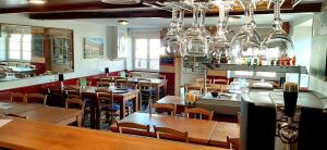 a restaurant with wooden tables and chairs and chandeliers at Le Marmagne in Marmagne