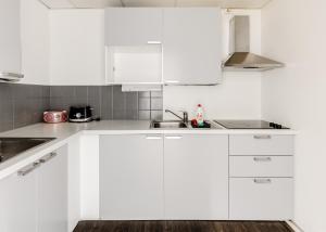 a white kitchen with white cabinets and a sink at Sky Hostel Helsinki in Helsinki