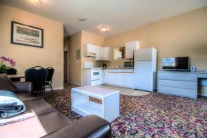 a living room with a couch and a kitchen at Creston Hotel & Suites in Creston