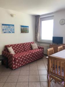 a living room with a red couch and a window at Appartamenti Penasa Renato in Commezzadura