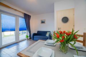 a living room with a blue couch and a table with flowers at Rellim Apartamenty in Władysławowo