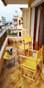 a balcony with yellow chairs and a table and a view of the ocean at Gerret in Can Picafort