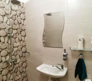 a bathroom with a sink and a shower with a mirror at Rila Apartment in Sofia