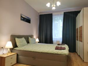 a bedroom with a bed with blue curtains and a window at Rila Apartment in Sofia