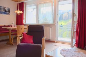 a living room with a chair and a table and windows at Steiert Panorama Apartments Todtnau in Todtnau