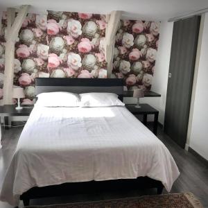 sypialnia z dużym łóżkiem z różowymi kwiatami w obiekcie Les Chambres d'Hotes chez Alisa et Daniel w mieście Sarlat-la-Canéda