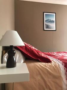 a bed with a red blanket and a table with a lamp at La Condaminoise in Condamine-Châtelard