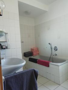 a white bathroom with a tub and a sink at Meyers Ferienwohnung in Elmlohe
