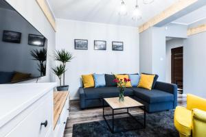 a living room with a blue couch and yellow chairs at Nosal Hill Apartments&Spa in Zakopane