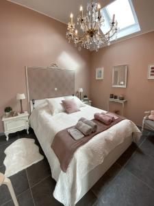 1 dormitorio con 1 cama grande y lámpara de araña en Gîte Côté Grange, en Philippeville