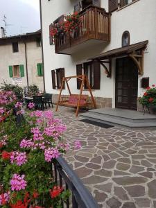 un patio con flores y un balcón con un columpio en Appartamenti Donini Marco, en Molveno